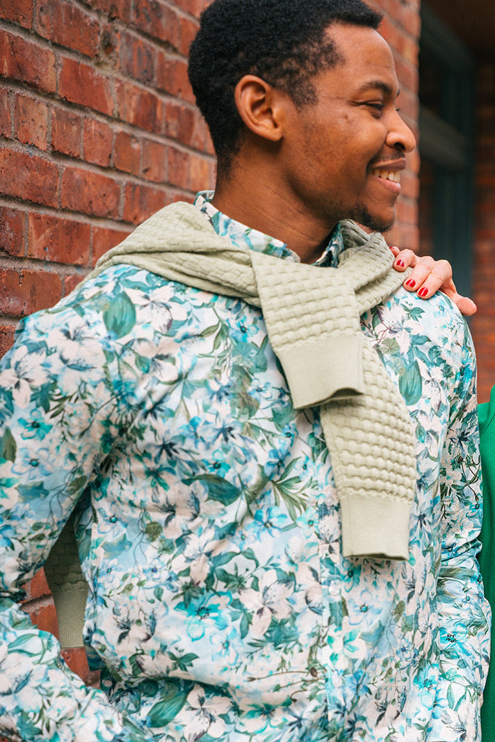 Two people standing on a street, both wearing floral-patterned clothing.