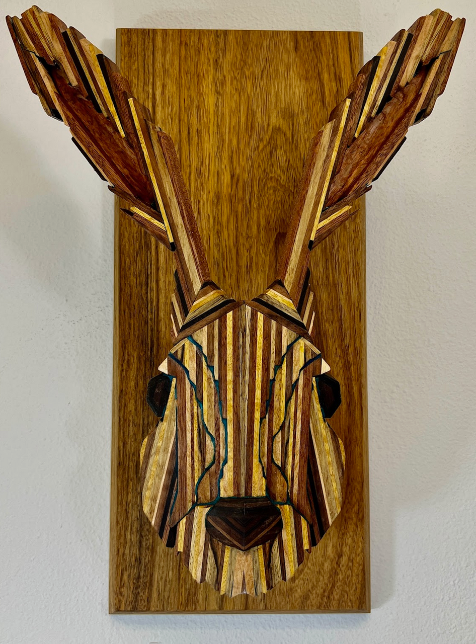 Rabbit head sculpture. Maple, Padauk, Lacewood, Movingia, Peruvian Walnut, Wenge, Black Limba, Iroko, Shedua woods, mounted on Shedua. Elevations of face highlighted by powdered Lapis Lazuli and blue tint epoxy.